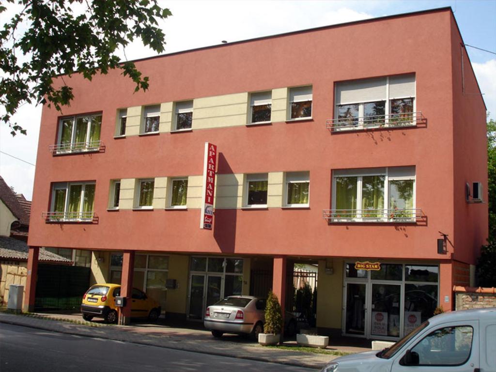 a red building with cars parked in front of it at Guesthouse Sava in Slavonski Brod