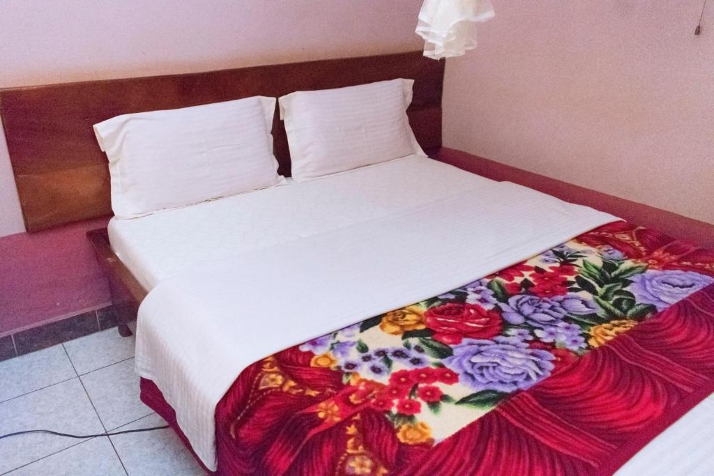 Una cama en una habitación de hotel con una manta de flores. en Starlight Hotel Mbale, en Mbale