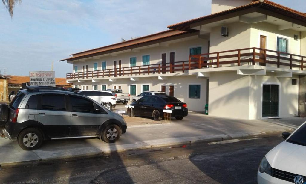 dos autos estacionados en un estacionamiento frente a una casa en Hotel Brio en Salinópolis