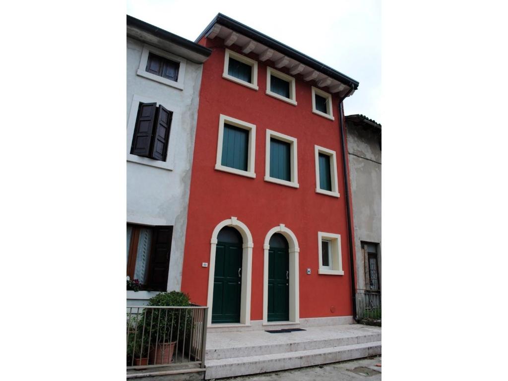 une maison rouge et blanche avec des fenêtres vertes dans l'établissement Bed And Breakfast Castello, à Villafranca di Verona