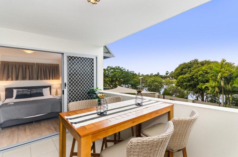 a dining table and chairs on a balcony with a bed at City Stadium Apartment on the riverfront in Townsville