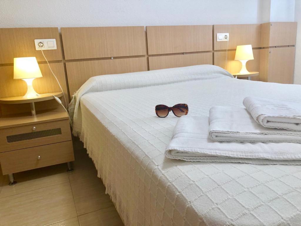Marina D´or Asequible apartamento في أوروبيسا ديل مار: وجود نظارة شمسية على سرير مع مناشف