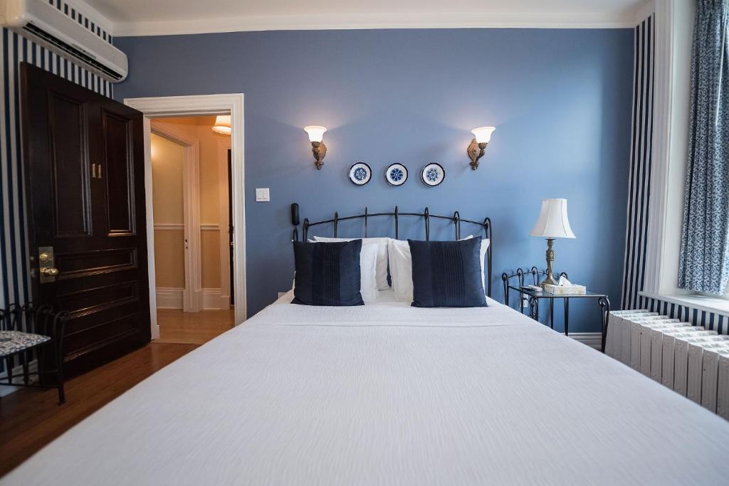 a bedroom with a large bed with blue walls at Manoir Sherbrooke in Montréal