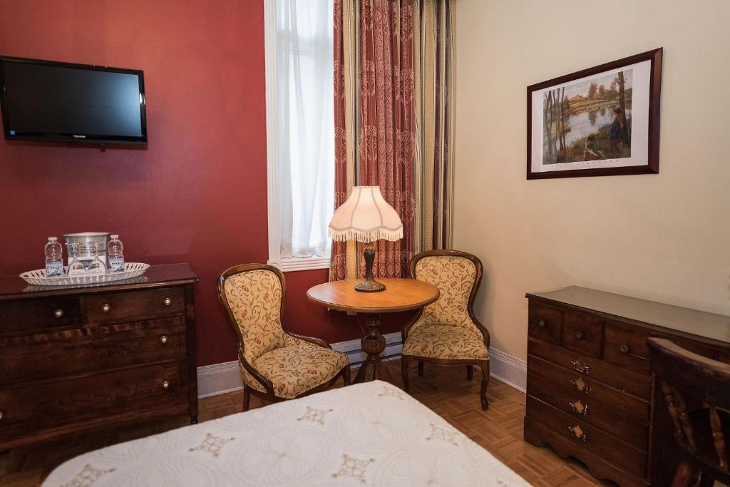 a bedroom with a table and two chairs and a bed at Manoir Sherbrooke in Montréal