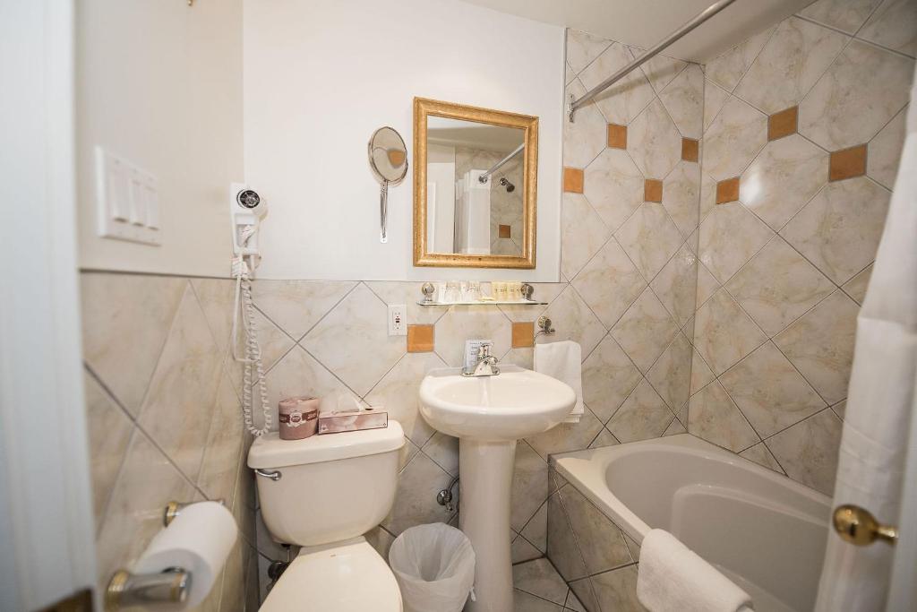 a bathroom with a sink and a toilet and a tub at Manoir Sherbrooke in Montréal