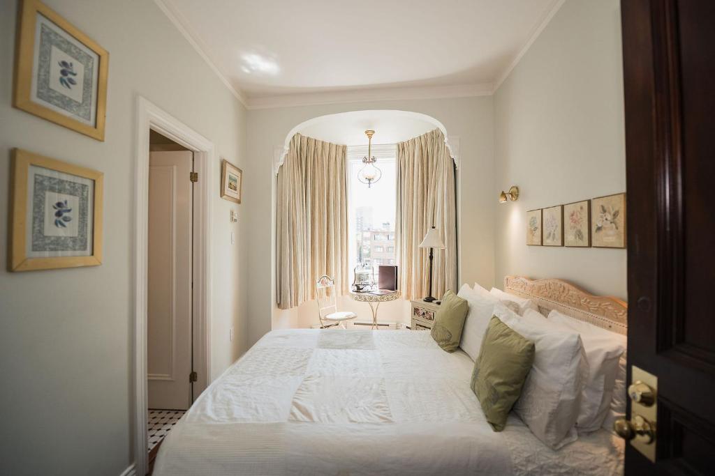 a bedroom with a white bed and a window at Manoir Sherbrooke in Montréal