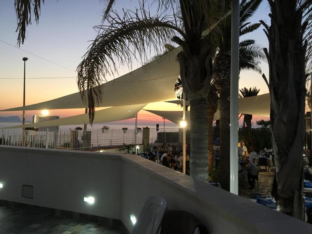 ein Restaurant am Strand bei Sonnenuntergang mit Palmen in der Unterkunft La Ruota B&B in Terrasini