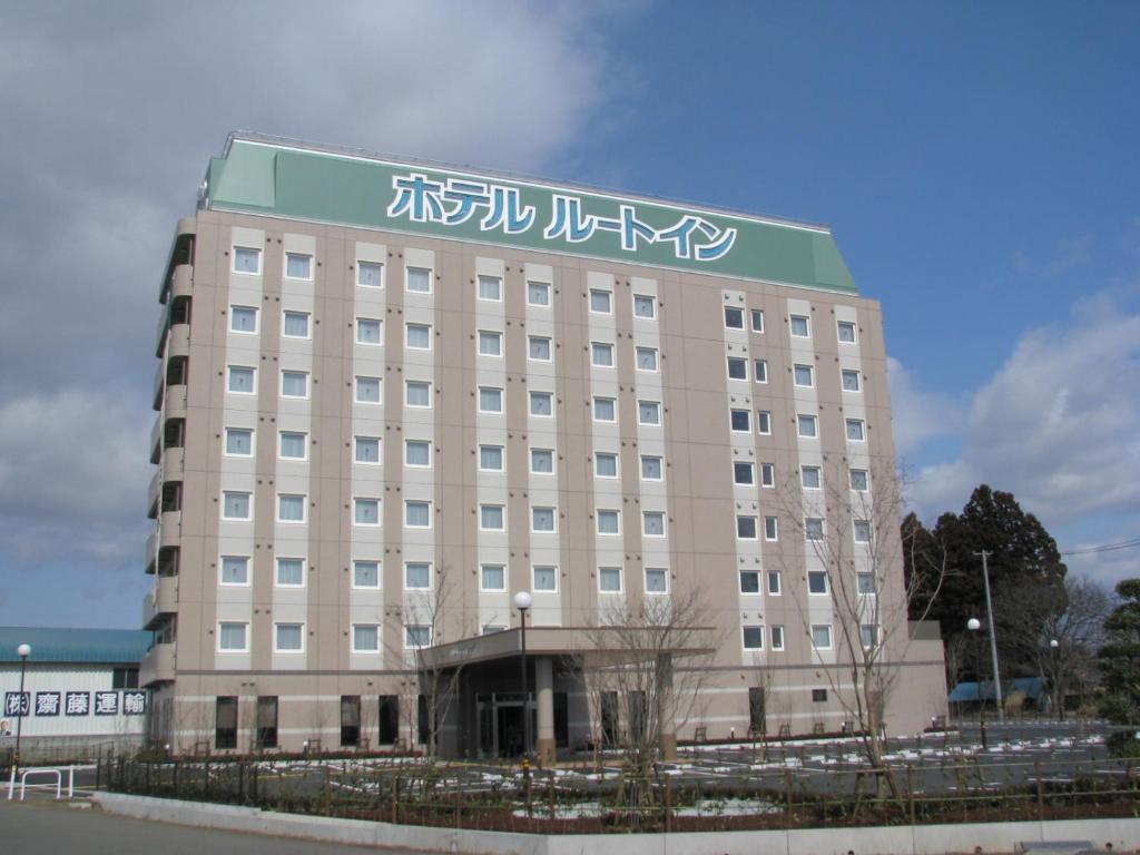 un grande edificio con scritte su un lato di Hotel Route-Inn Hanamaki a Hanamaki