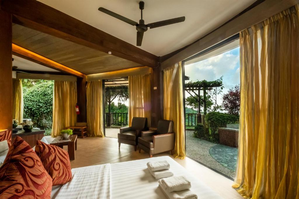 una camera da letto con un letto e una sedia e una grande finestra di West 35 Eco Mountain Resort a Balamban