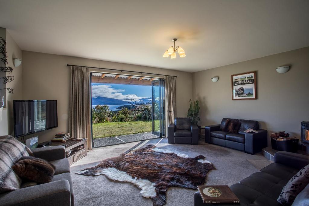 a living room with a couch and a tv and a large window at Loch Vista Bed & Breakfast in Te Anau