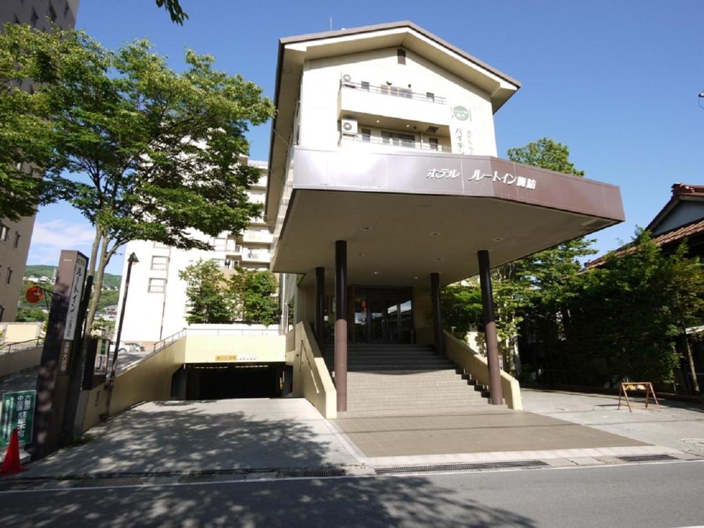 
a large building with a clock on the front of it at Hotel Route-Inn Kamisuwa in Suwa
