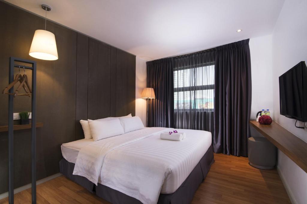 a bedroom with a large white bed with a window at T+ Hotel Butterworth in Butterworth