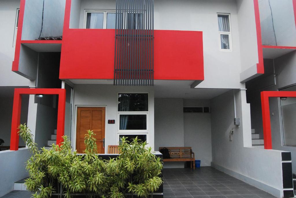 un bâtiment rouge et blanc avec des plantes devant lui dans l'établissement Wisma Andany, à Jepara