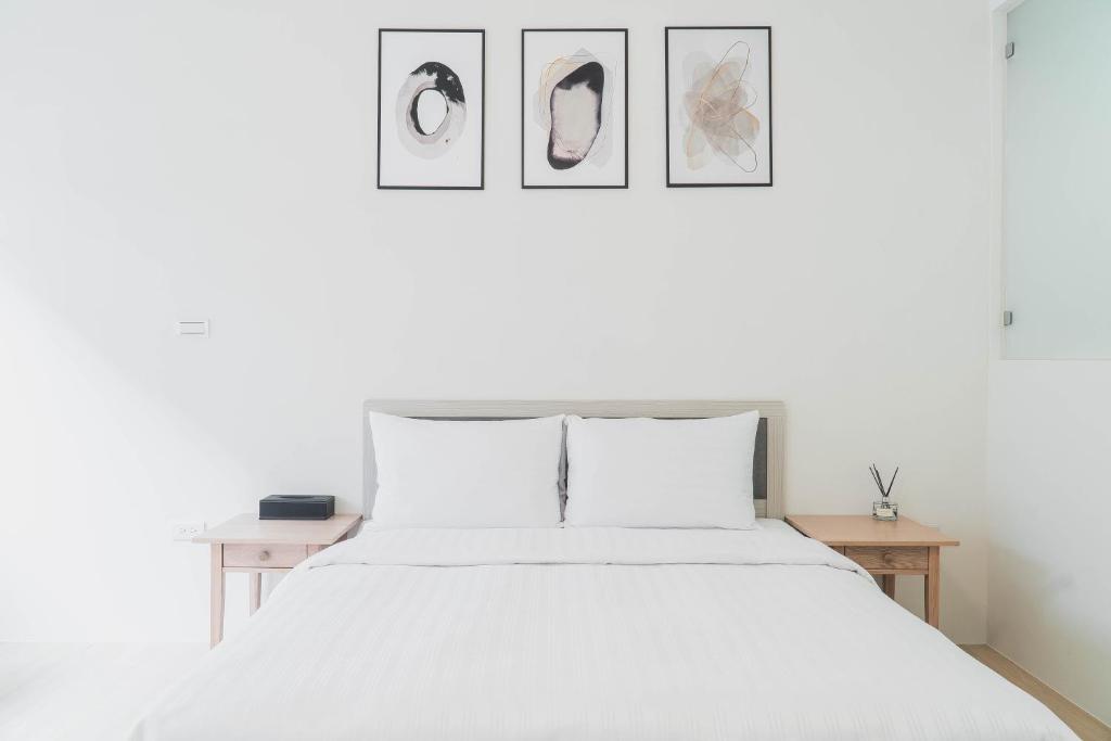 a bedroom with a white bed with three pictures on the wall at Boléro Homestay in Tainan