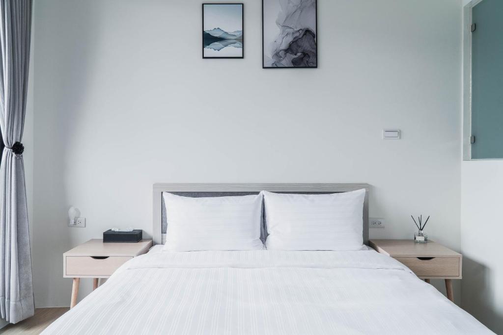 um quarto com uma cama branca com três fotografias na parede em Boléro Homestay em Tainan