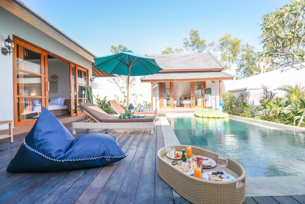 eine Terrasse mit einem Pool mit einem Tisch und einem Sonnenschirm in der Unterkunft Villa Kupu Kupu Bingin in Uluwatu