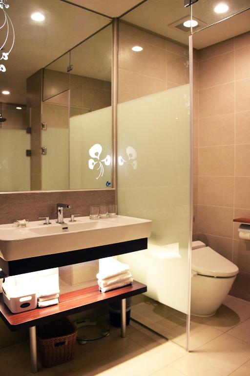a bathroom with a sink and a toilet and a mirror at Golden Tulip Glory Fine Hotel in Tainan