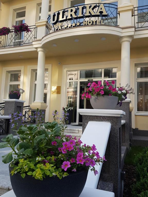 a garden area with a balcony with flowers in front of it at Spa Hotel ULRIKA in Karlovy Vary