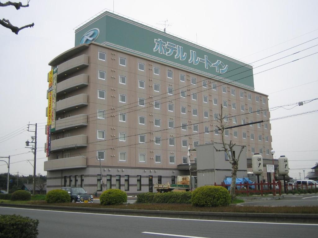 un grand bâtiment avec un panneau sur son côté dans l'établissement Hotel Route-Inn Hamamatsu Nishi Inter, à Hamamatsu