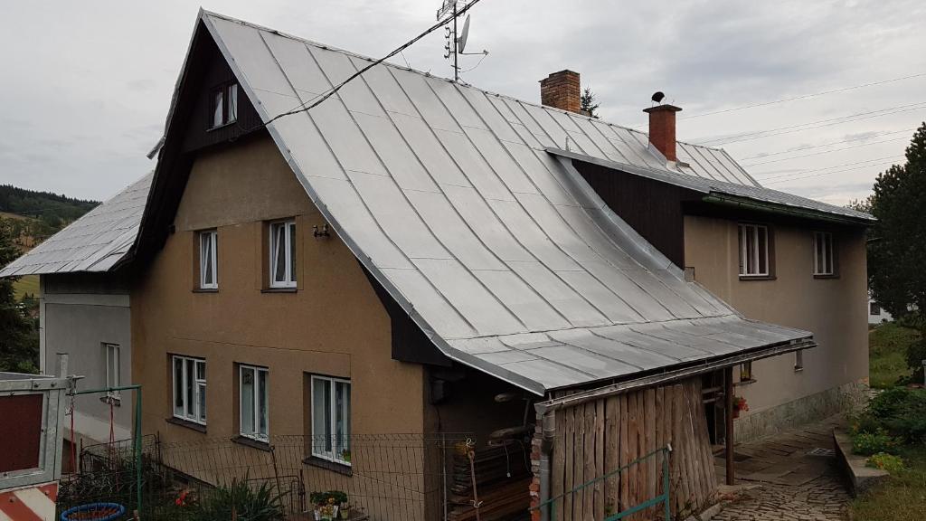 ein Haus mit einem Metalldach darüber in der Unterkunft Apartmany Pohořaly in Rokytnice nad Jizerou