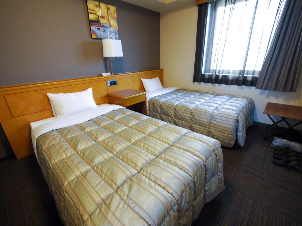 a hotel room with two beds and a window at Hotel Route-Inn Hamamatsu Eki Higashi in Hamamatsu
