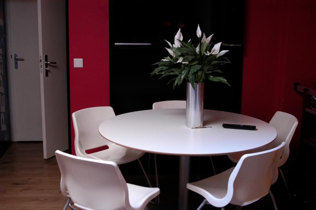 Una mesa blanca con sillas blancas y un jarrón de flores. en Rembrandt Square Hotel, en Ámsterdam