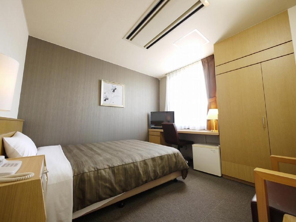 ein Hotelzimmer mit einem Bett und einem Schreibtisch mit einem Computer in der Unterkunft Hotel Route-Inn Seibu Chichibu Ekimae in Chichibu