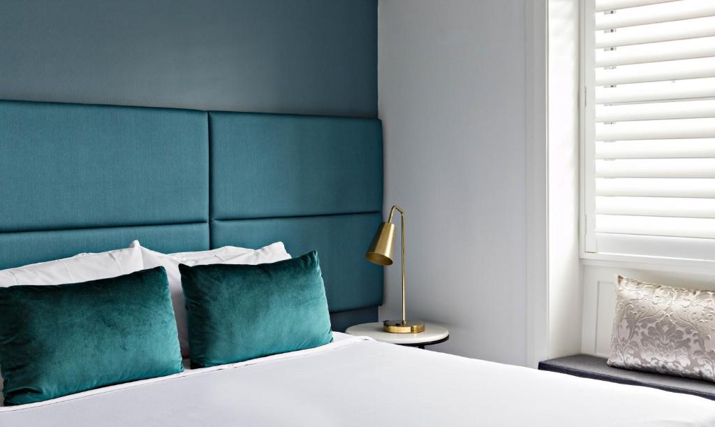Avoca Randwick by Sydney Lodges في سيدني: غرفة نوم مع سرير مع اللوح الأمامي الأزرق والوسائد