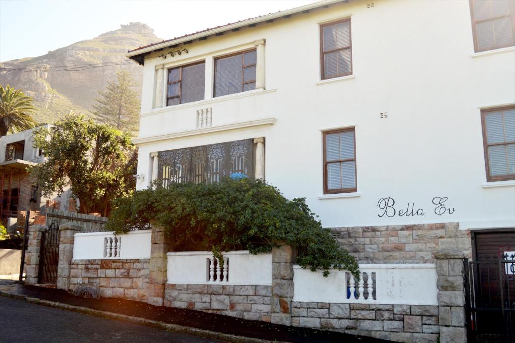 a white house with a stone wall at Bella Ev Guest House in Muizenberg
