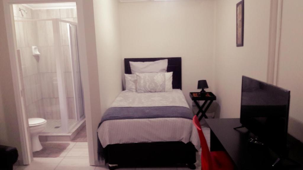 a small bedroom with a bed and a television at Zanevovo in Scottburgh