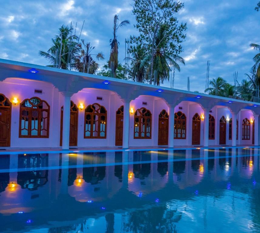 a villa with a swimming pool at night at MRD Beach Hotel in Trincomalee