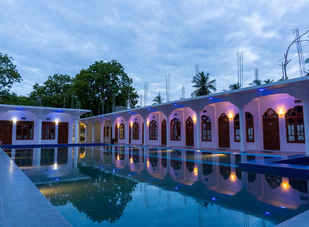 a building with a swimming pool at night at MRD Beach Hotel in Trincomalee