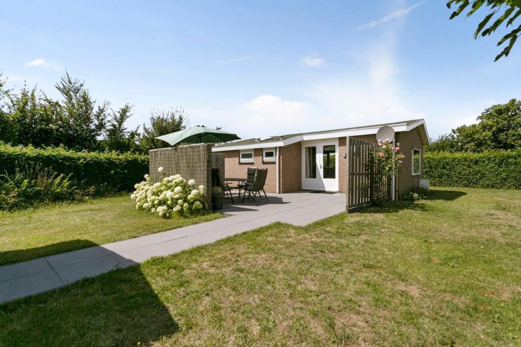 a tiny house in a garden with a patio at Bungalow De krukel - Ouddorp fenced garden, near the beach and dunes - not for companies in Ouddorp