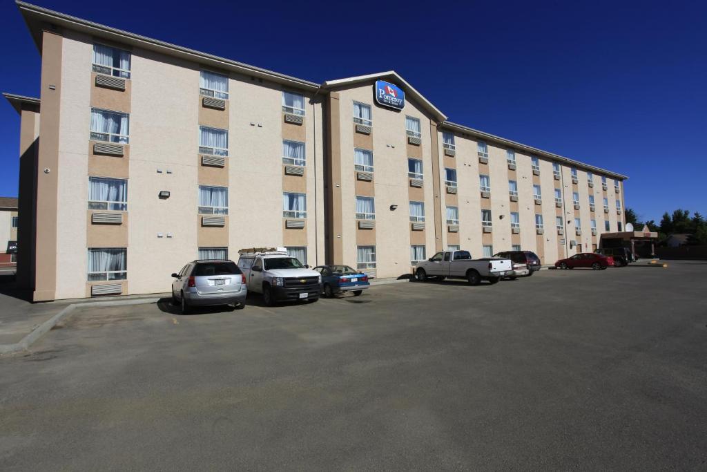 ein großes Gebäude mit Autos auf einem Parkplatz in der Unterkunft Pomeroy Inn & Suites Fort St. John in Fort Saint John