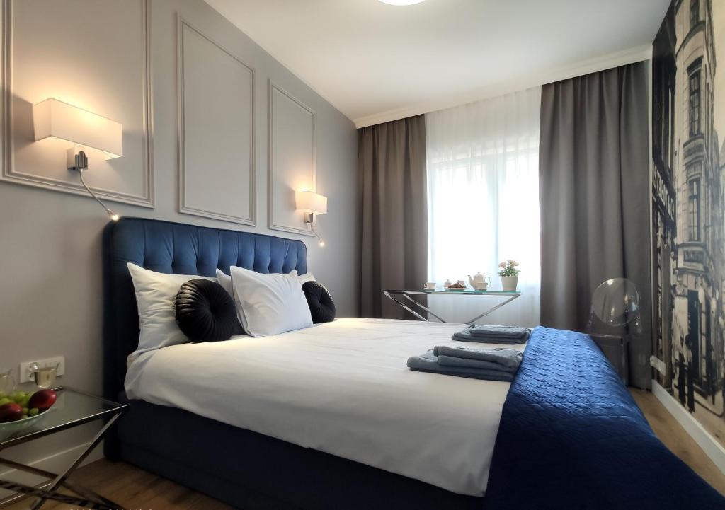a bedroom with a large bed with a blue headboard at Prestige Apartment Słupsk in Słupsk