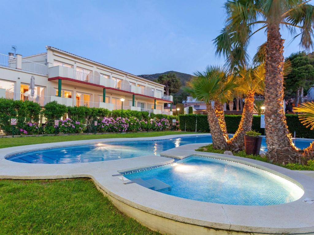 uma piscina com palmeiras e um edifício em Apartment Palmiers I-7 by Interhome em Llançà
