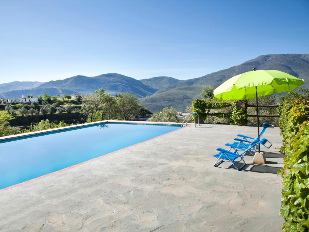 una piscina con sombrilla verde y sillas azules en Holiday Home El Cerrillo - Cerro Negro by Interhome, en Órgiva