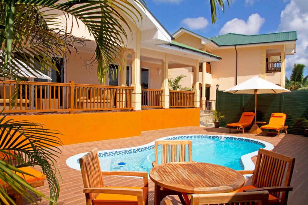 patio ze stołem i krzesłami oraz basenem w obiekcie The Palm Seychelles w mieście Bel Ombre