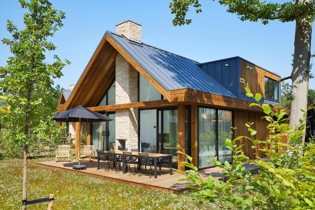 a house with a wooden deck with a table and chairs at Landgoed Bergvliet in Oosterhout