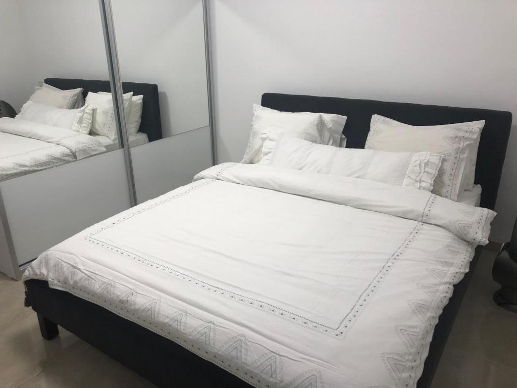 a large bed with white sheets and pillows at The Urban Apartment in Haifa