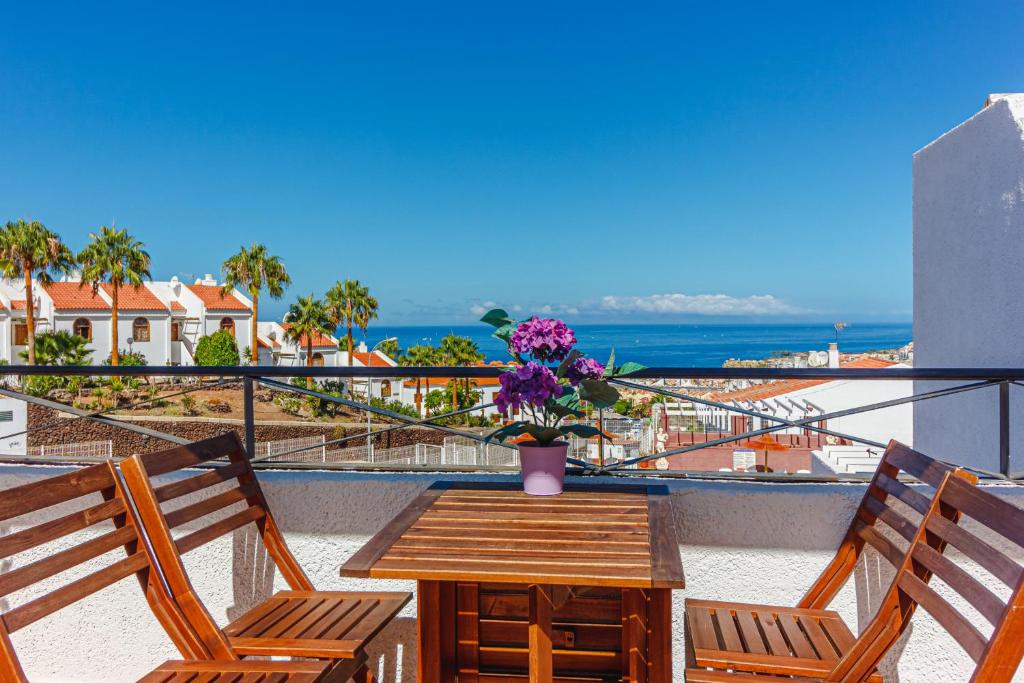 einen Balkon mit 2 Stühlen und einem Tisch mit Blumen in der Unterkunft Apartment with ocean view in Costa Adeje in Adeje