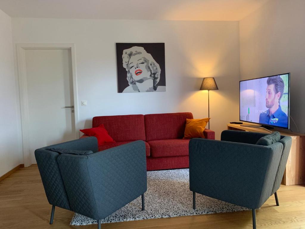 ローゼンハイムにあるFerienwohnungen Reschenhofのリビングルーム(赤いソファ、椅子2脚付)