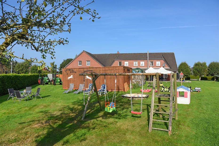 a playground in a yard with a house at Ferienhof zur alten Linde in Holtgast