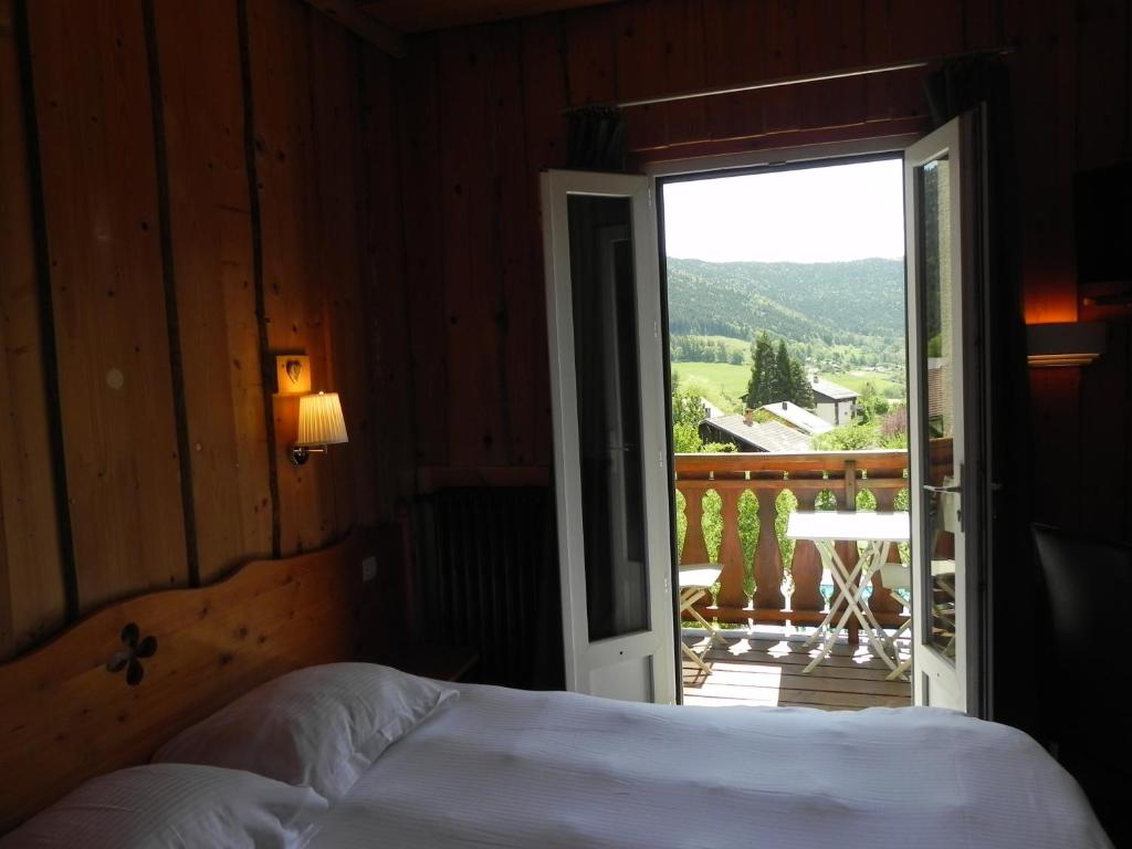 a bedroom with a bed and a door leading to a balcony at Hôtel des Skieurs in Le Sappey-en-Chartreuse