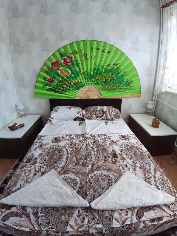 Schlafzimmer mit einem großen Bett mit einem grünen Kopfteil in der Unterkunft Малко oазисче in Sofia