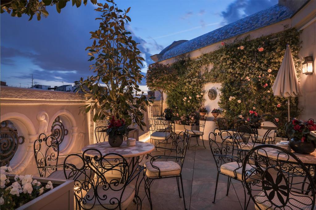 eine Außenterrasse mit Tischen, Stühlen und Pflanzen in der Unterkunft Relais & Châteaux Heritage Hotel in Madrid