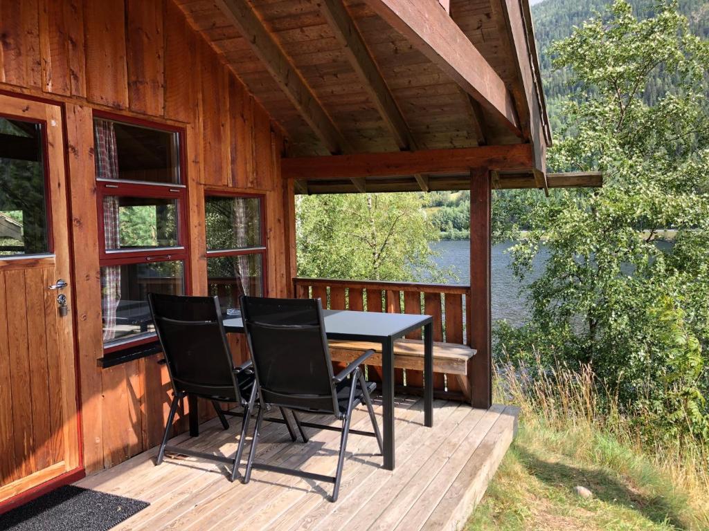 a table and chairs on the porch of a cabin at Fjordgløtt Camping/Hytter in Rødberg