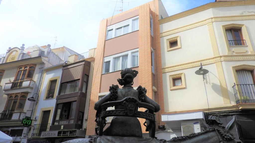 uma estátua de uma mulher sentada numa cadeira em frente aos edifícios em Viviendas con Fines Turisticos ``La Jamuga´´ em Andújar