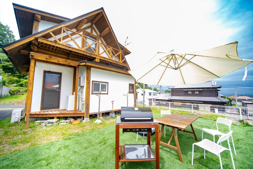 a small house with a table and an umbrella at Awaji Seaside Log House in Awaji