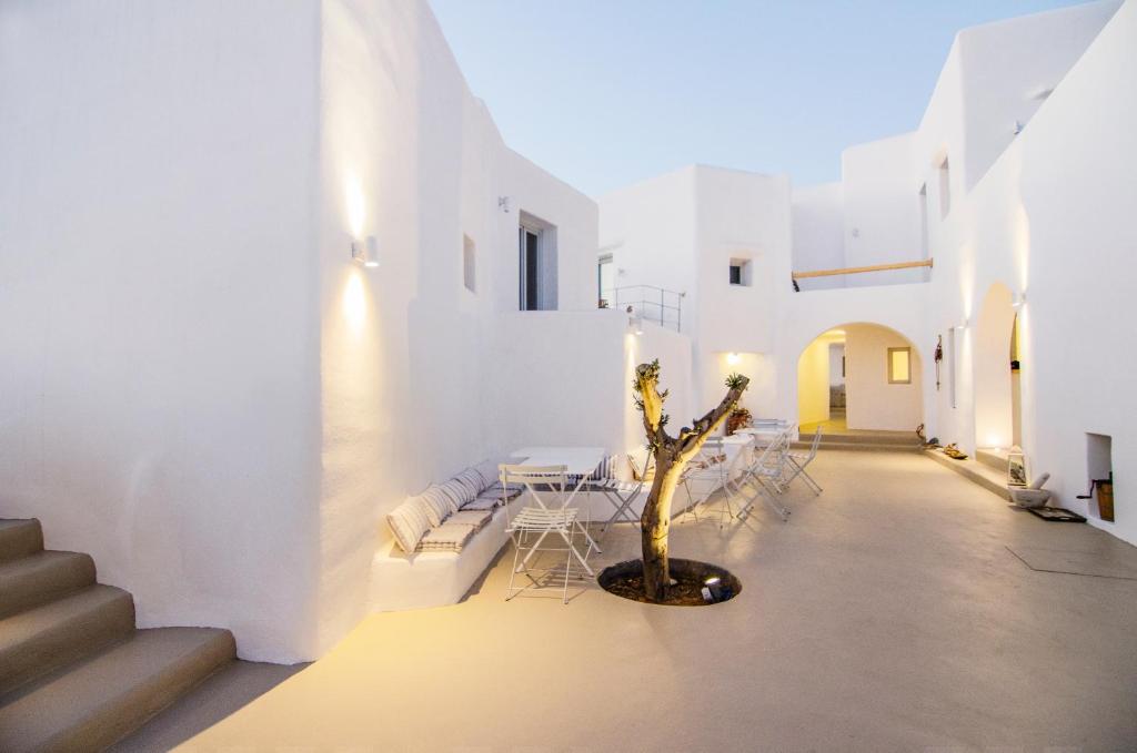 a courtyard with white walls and a tree in the middle at White Loft in Ios Chora
